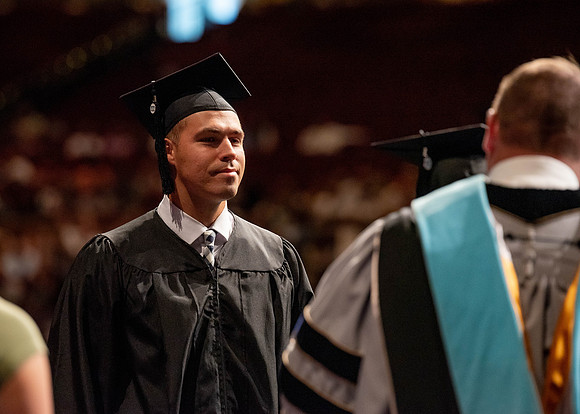 Students partipate in walking to graduate from the College of Business and Communication.