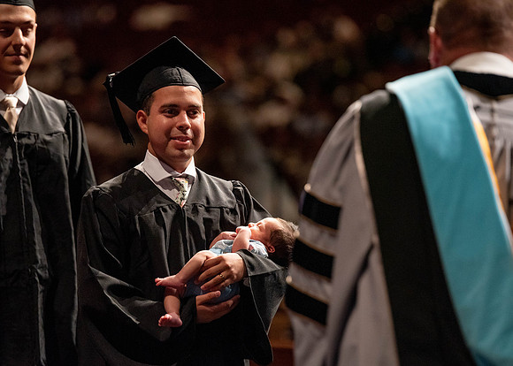 Students partipate in walking to graduate from the College of Business and Communication.