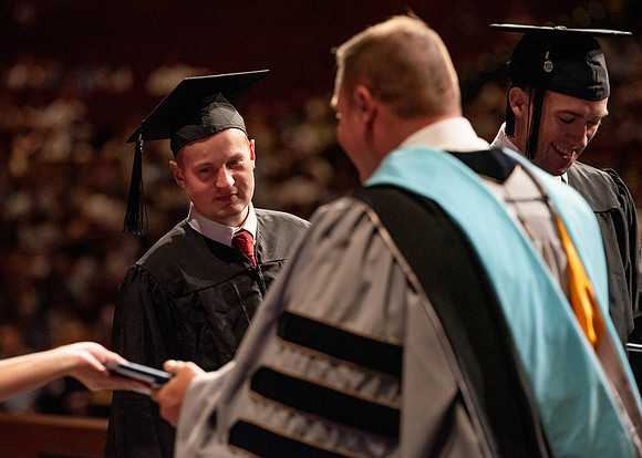 Students partipate in walking to graduate from the College of Business and Communication.