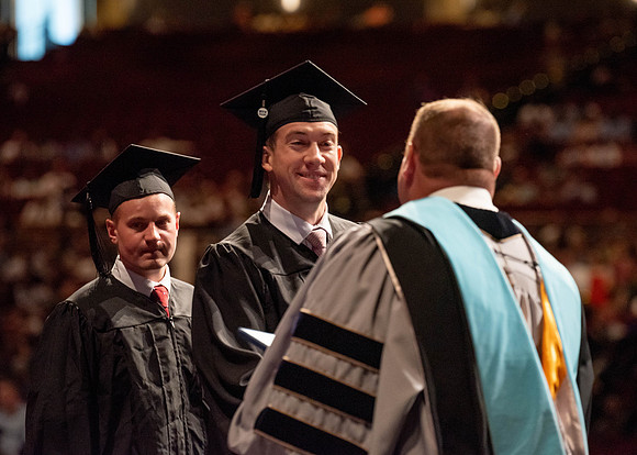 Students partipate in walking to graduate from the College of Business and Communication.