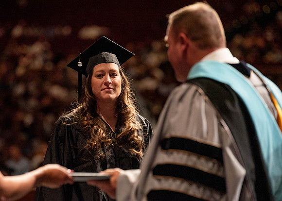 Students partipate in walking to graduate from the College of Business and Communication.