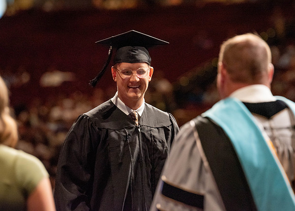 Students partipate in walking to graduate from the College of Business and Communication.