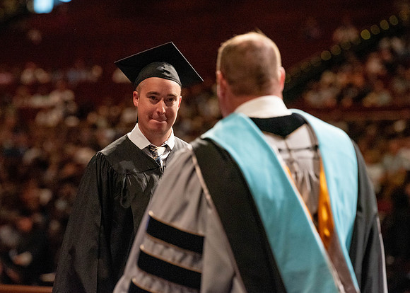 Students partipate in walking to graduate from the College of Business and Communication.