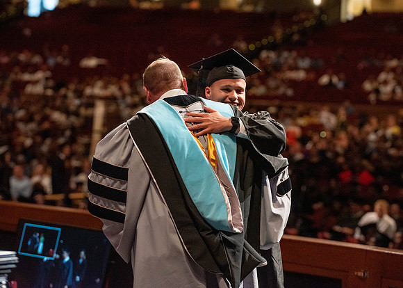 Students partipate in walking to graduate from the College of Business and Communication.