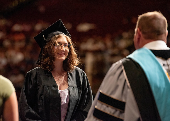 Students partipate in walking to graduate from the College of Business and Communication.