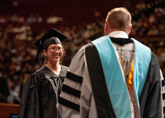 Students partipate in walking to graduate from the College of Business and Communication.