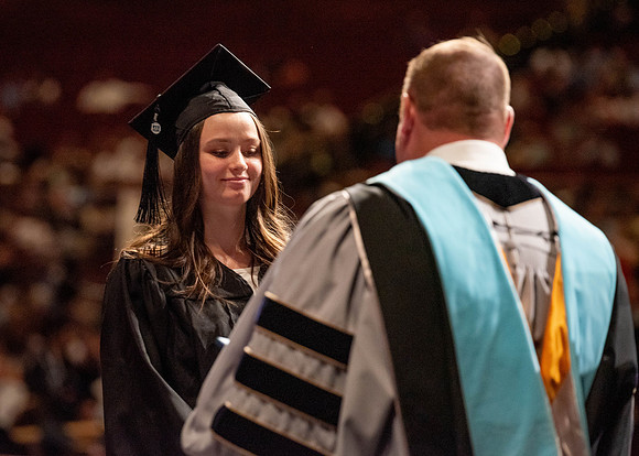 Students partipate in walking to graduate from the College of Business and Communication.