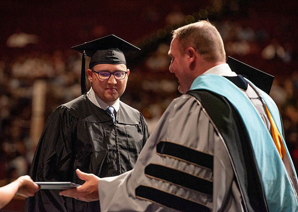 Students partipate in walking to graduate from the College of Business and Communication.