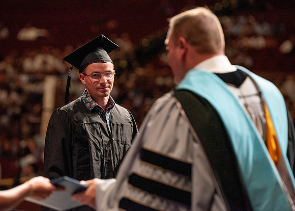 Students partipate in walking to graduate from the College of Business and Communication.