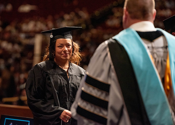 Students partipate in walking to graduate from the College of Business and Communication.