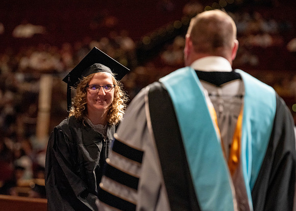 Students partipate in walking to graduate from the College of Business and Communication.