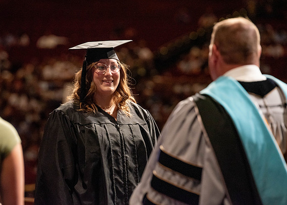 Students partipate in walking to graduate from the College of Business and Communication.
