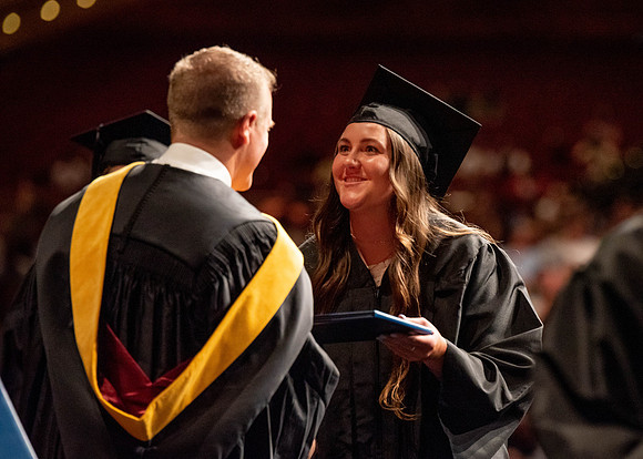 Students partipate in walking to graduate from the College of Business and Communication.
