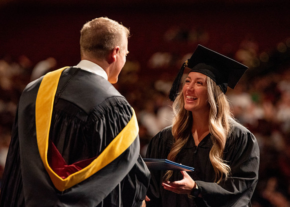 Students partipate in walking to graduate from the College of Business and Communication.