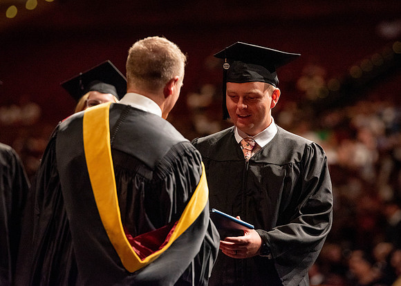 Students partipate in walking to graduate from the College of Business and Communication.