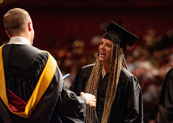 Students partipate in walking to graduate from the College of Business and Communication.
