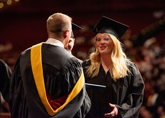 Students partipate in walking to graduate from the College of Business and Communication.
