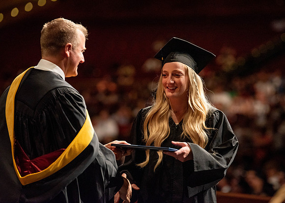 Students partipate in walking to graduate from the College of Business and Communication.