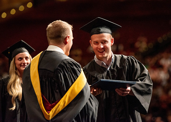 Students partipate in walking to graduate from the College of Business and Communication.