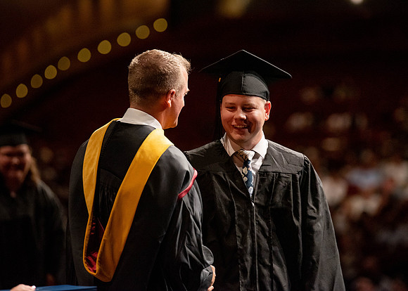 Students partipate in walking to graduate from the College of Business and Communication.