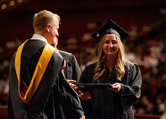 Students partipate in walking to graduate from the College of Business and Communication.
