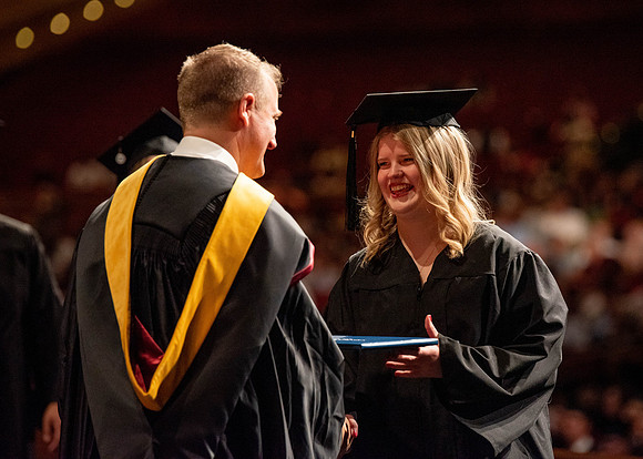 Students partipate in walking to graduate from the College of Business and Communication.