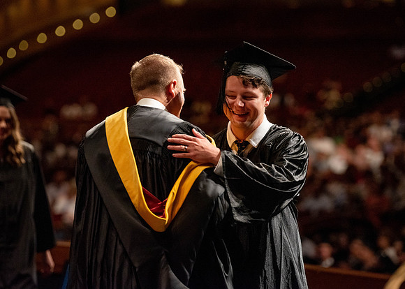 Students partipate in walking to graduate from the College of Business and Communication.