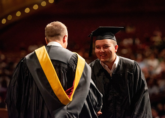 Students partipate in walking to graduate from the College of Business and Communication.