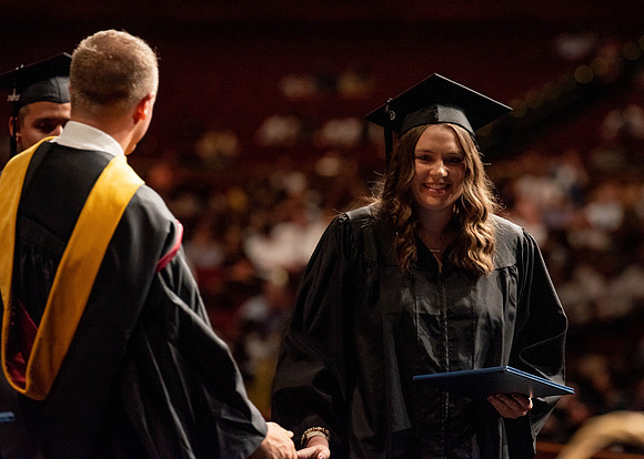 Students partipate in walking to graduate from the College of Business and Communication.