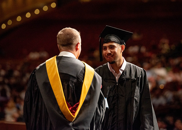 Students partipate in walking to graduate from the College of Business and Communication.