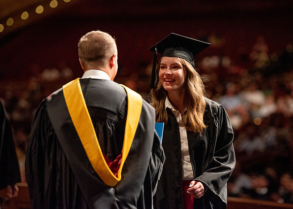 Students partipate in walking to graduate from the College of Business and Communication.