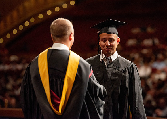Students partipate in walking to graduate from the College of Business and Communication.