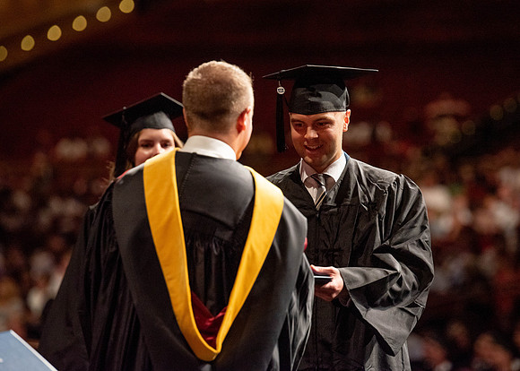 Students partipate in walking to graduate from the College of Business and Communication.