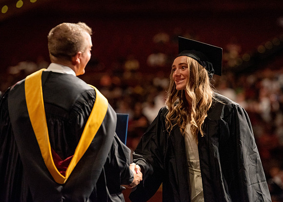 Students partipate in walking to graduate from the College of Business and Communication.