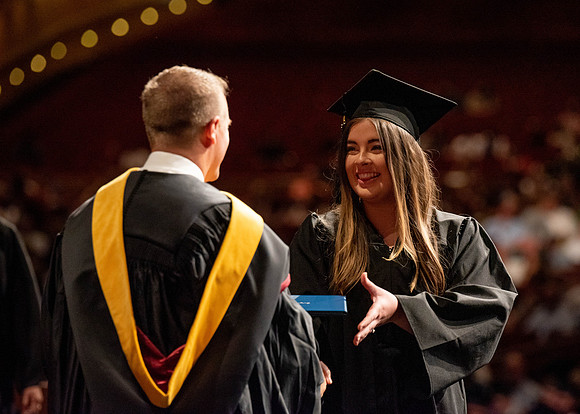 Students partipate in walking to graduate from the College of Business and Communication.
