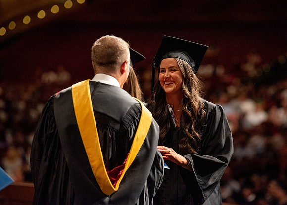 Students partipate in walking to graduate from the College of Business and Communication.