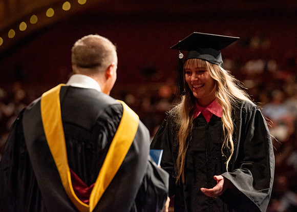 Students partipate in walking to graduate from the College of Business and Communication.