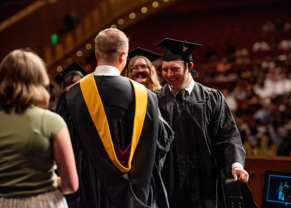 Students partipate in walking to graduate from the College of Business and Communication.