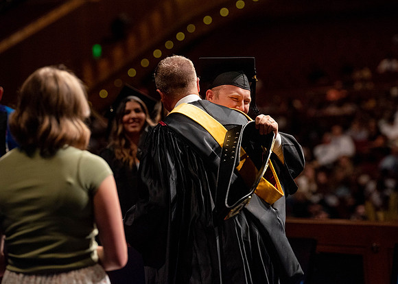Students partipate in walking to graduate from the College of Business and Communication.
