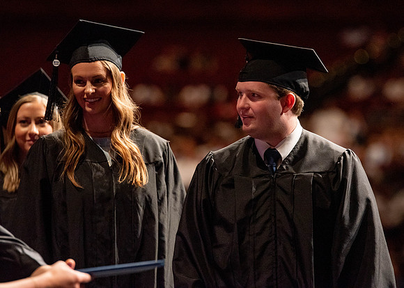 Students partipate in walking to graduate from the College of Business and Communication.