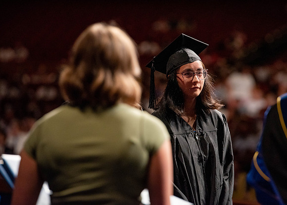 Students partipate in walking to graduate from the College of Business and Communication.