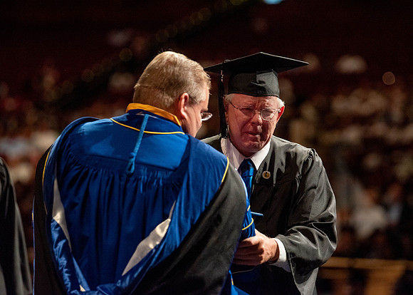 Students partipate in walking to graduate from the College of Business and Communication.