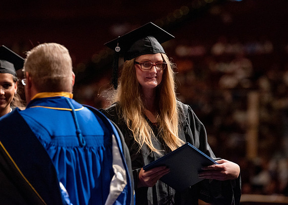 Students partipate in walking to graduate from the College of Business and Communication.