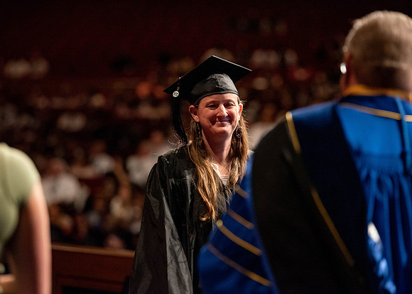 Students partipate in walking to graduate from the College of Business and Communication.