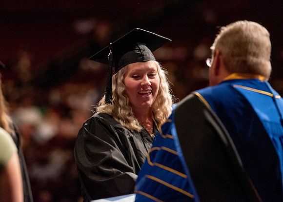 Students partipate in walking to graduate from the College of Business and Communication.
