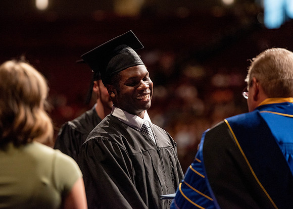 Students partipate in walking to graduate from the College of Business and Communication.
