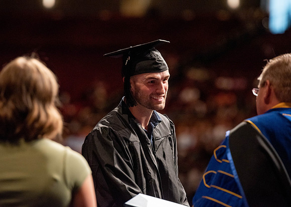 Students partipate in walking to graduate from the College of Business and Communication.