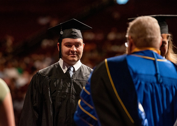 Students partipate in walking to graduate from the College of Business and Communication.