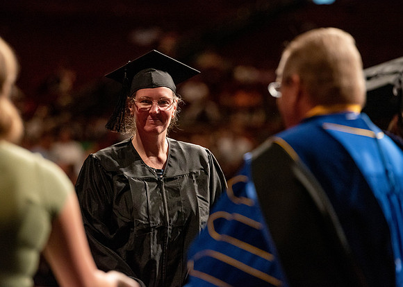 Students partipate in walking to graduate from the College of Business and Communication.