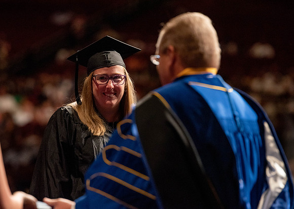Students partipate in walking to graduate from the College of Business and Communication.